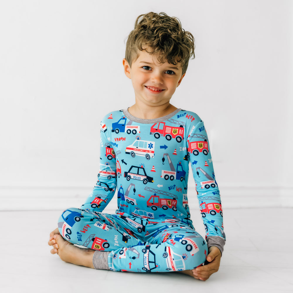 Child sitting wearing a To The Rescue two piece pajama set