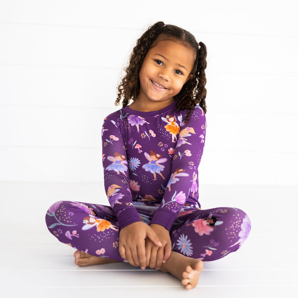 Smiling girl sitting while wearing the Garden Fairies Two-Piece Pajama Set