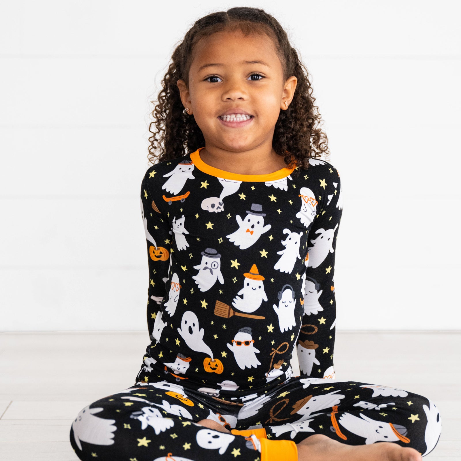 Girl sitting while wearing the Friendly Ghosts Two-Piece Pajama Set