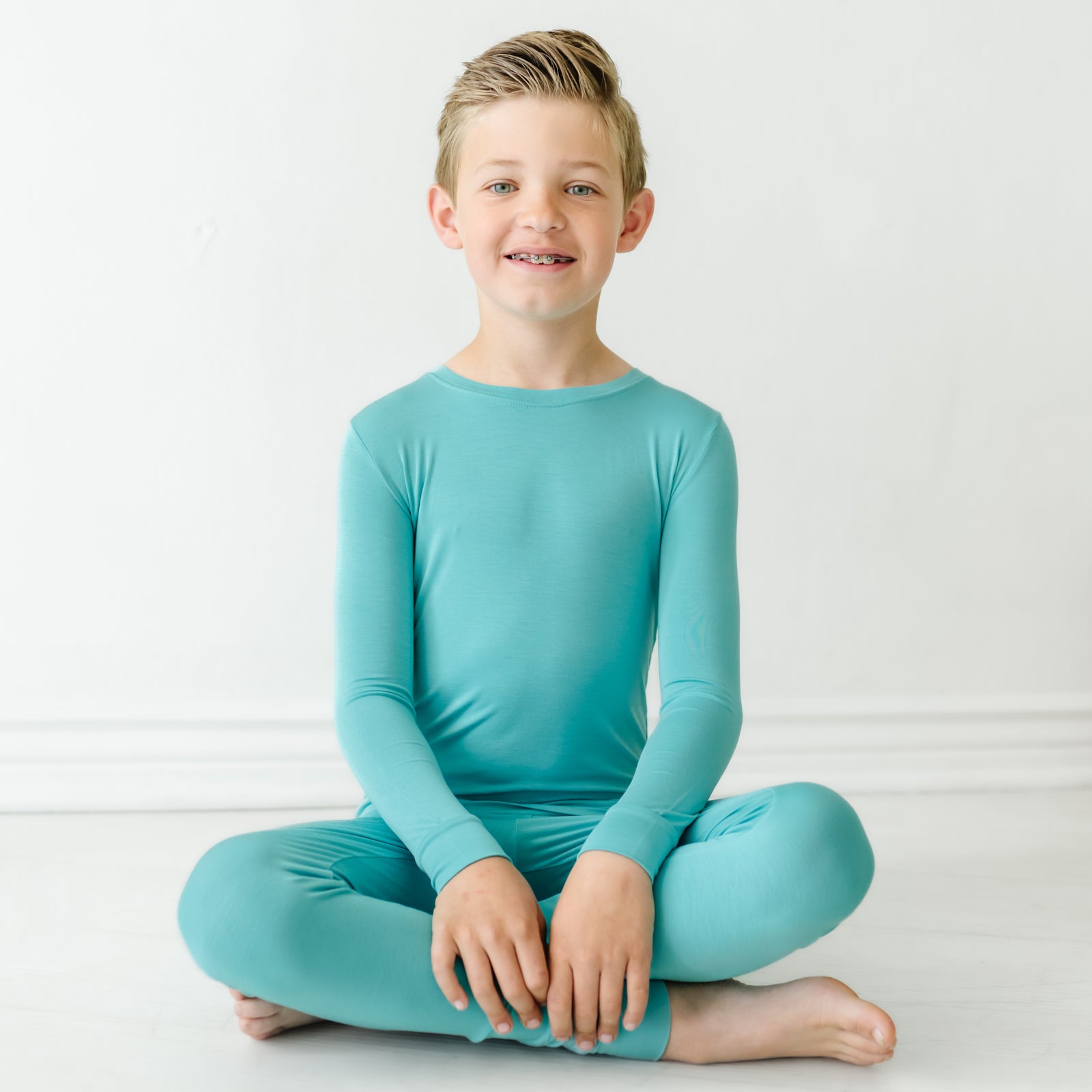child sitting posing wearing Glacier Turquoise two piece pajama set