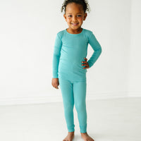 child posing wearing Glacier Turquoise two piece pajama set