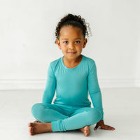 alternate image of a child sitting and posing wearing Glacier Turquoise two piece pajama set