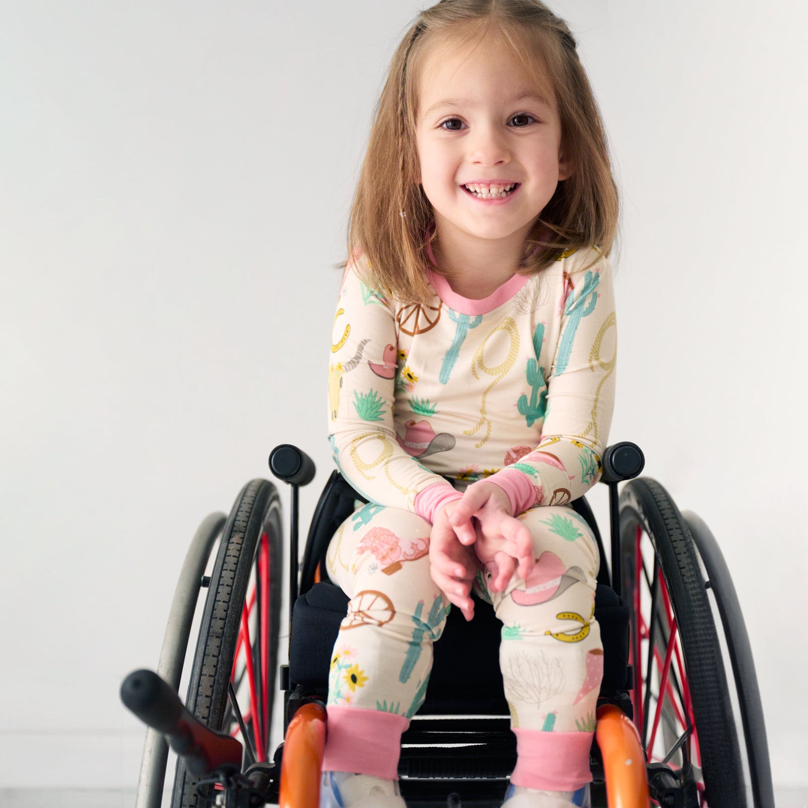 Child in a wheelchair wearing a Pink Ready to Rodeo two piece pajama set
