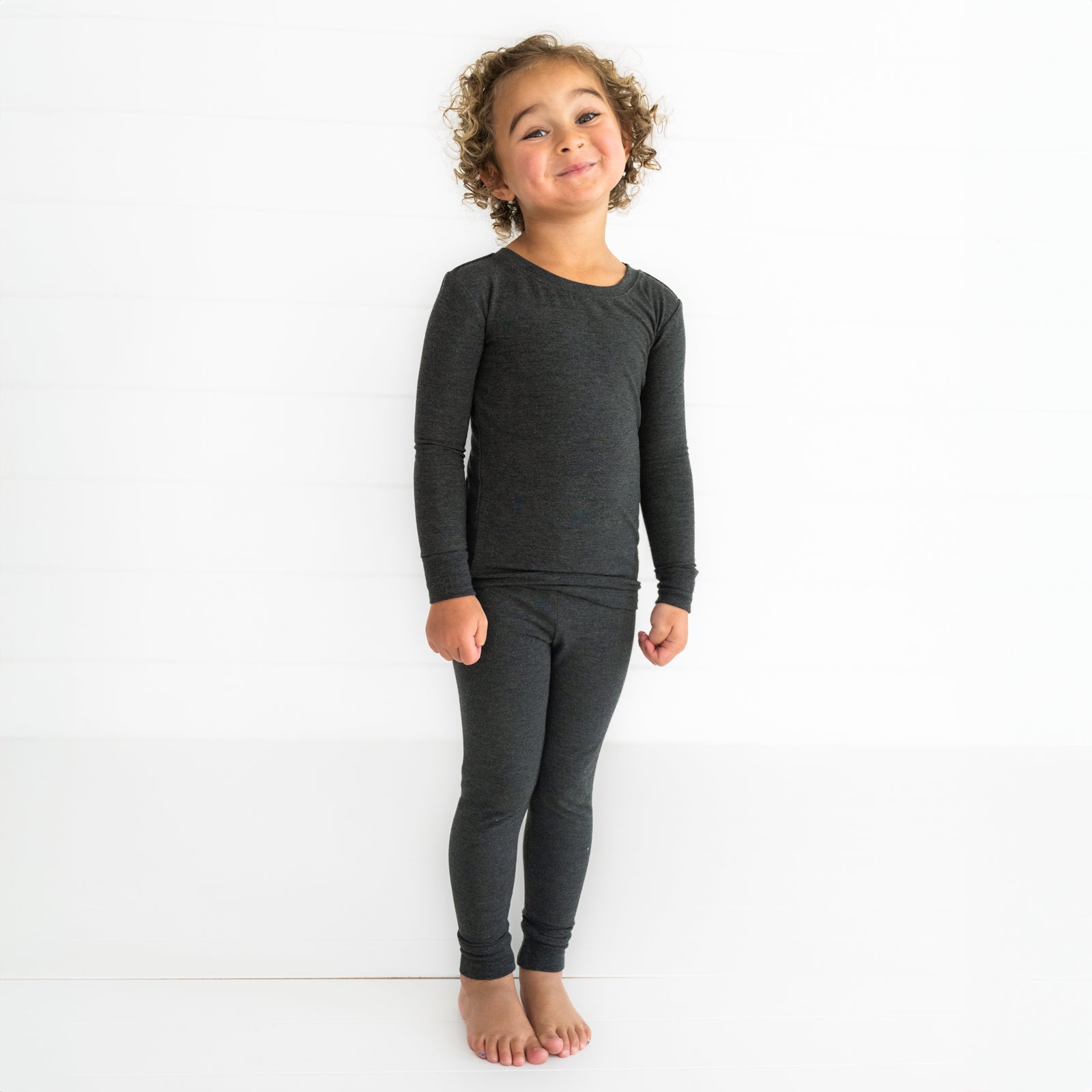 Child posing wearing a Cozy Heather Black two piece pj set