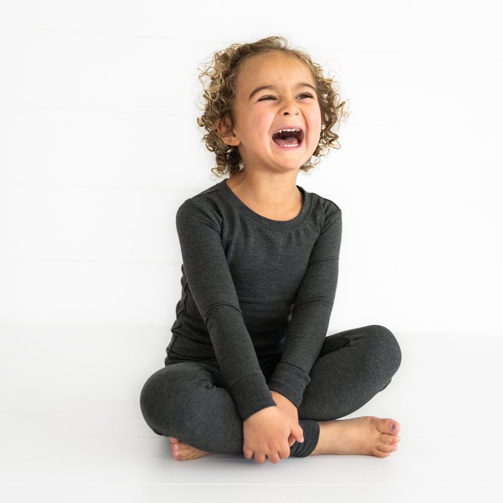 Child sitting wearing a Cozy Heather Black two piece pj set