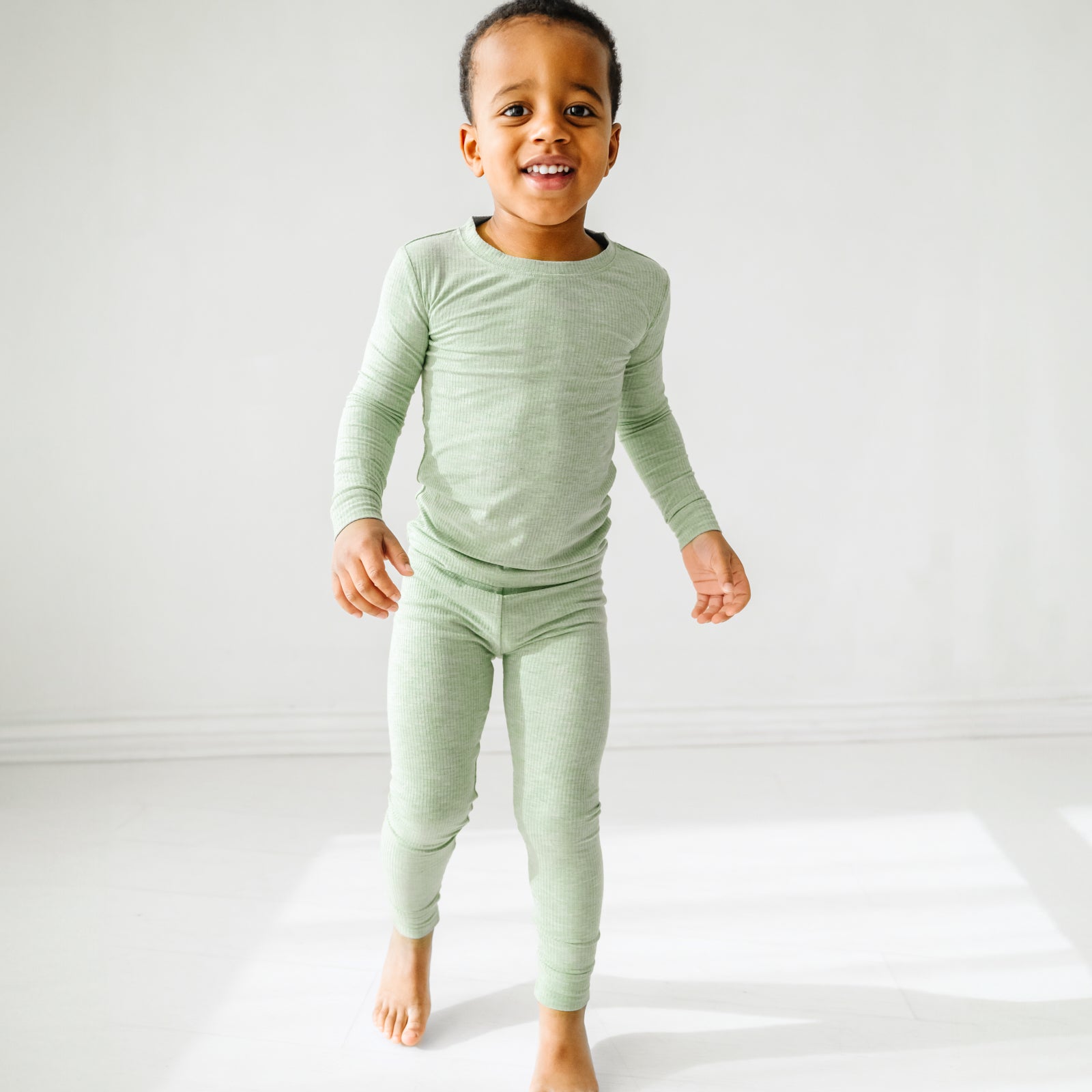 Child playing wearing a Heather Sage two piece pajama set