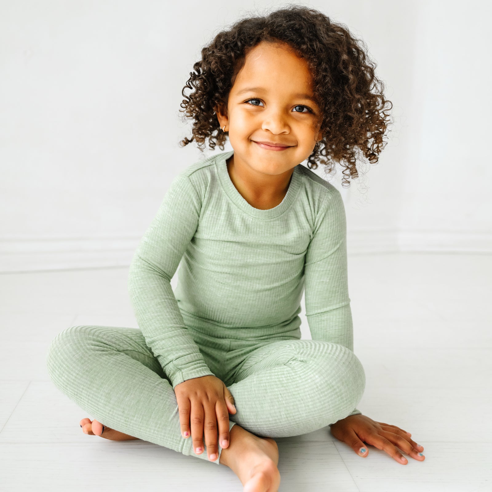 Child sitting wearing a Heather Sage two piece pajama set