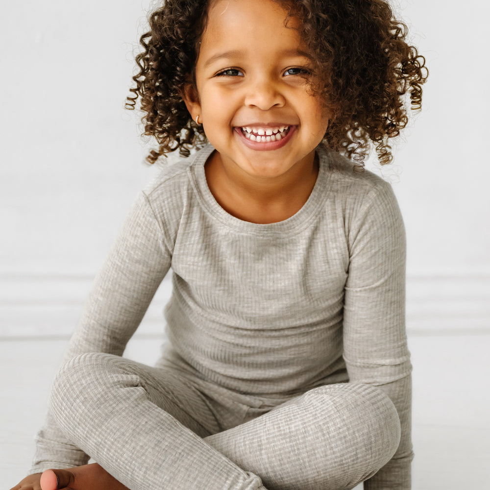 Click to see full screen - Close up image of a child sitting wearing a Heather Stone Ribbed two piece pajama set