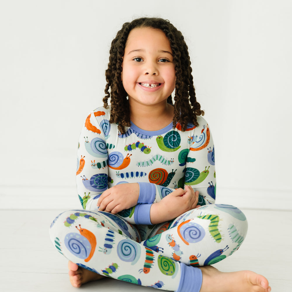 Child sitting on the ground wearing an Inchin' Along two-piece pajama set