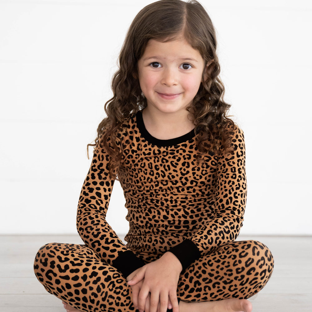 Girl sitting while wearing the Classic Leopard Two-Piece Pajama Set