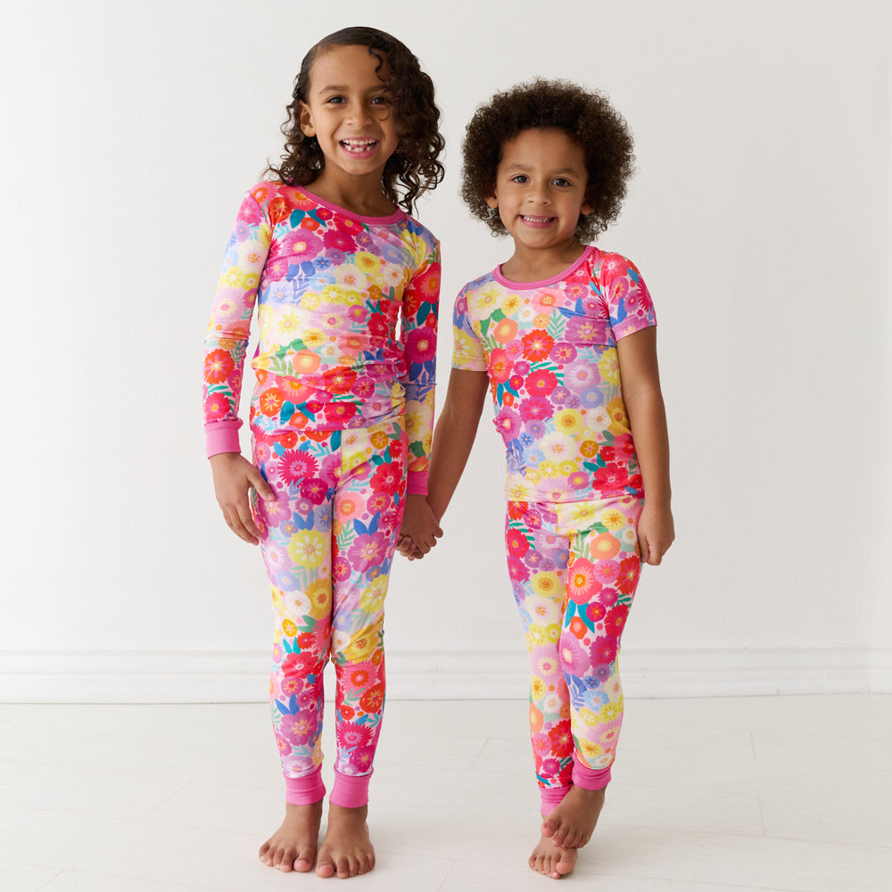Two children holding hands wearing matching Rainbow Blooms pajamas