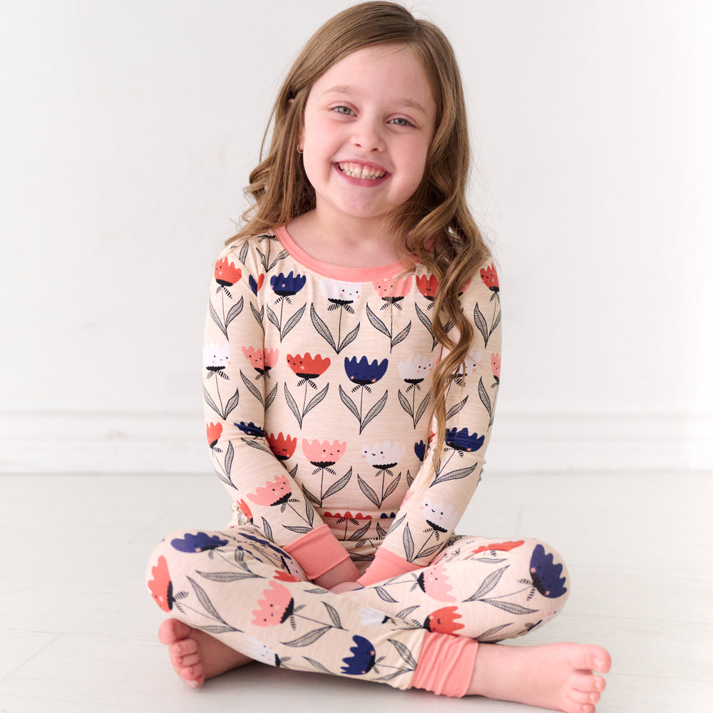Child sitting on the ground wearing a Flower Friends two-piece pajama set