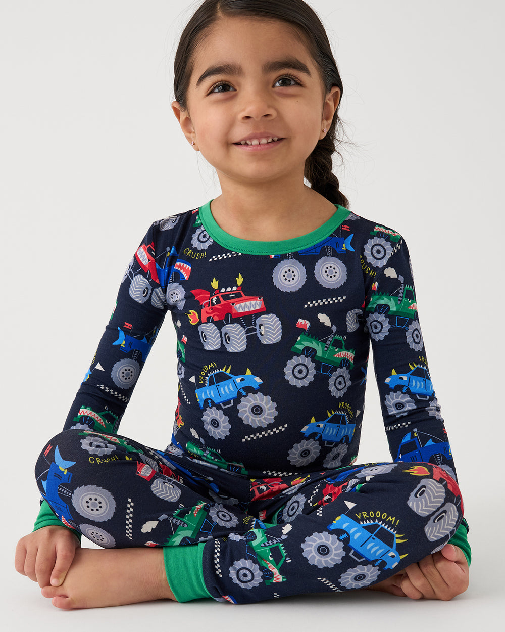 Sitting girl wearing the Monster Truck Madness Two-Piece Pajama Set