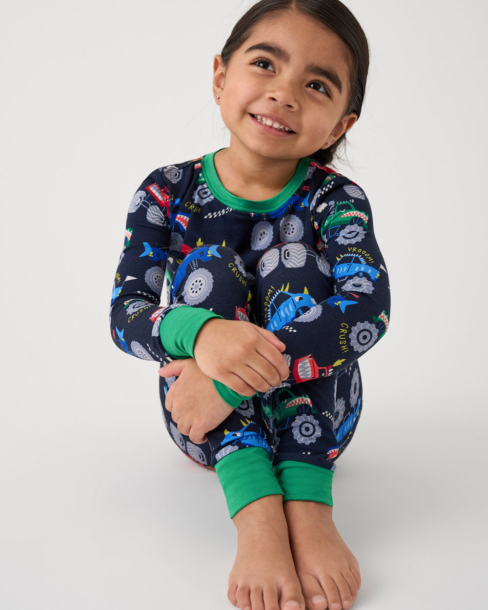 Close up of sitting girl wearing the Monster Truck Madness Two-Piece Pajama Set