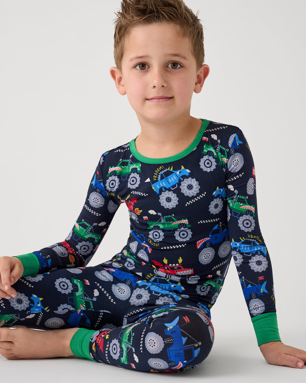 Sitting boy wearing the Monster Truck Madness Two-Piece Pajama Set