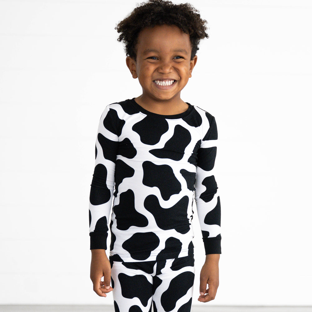 Boy smiling while in the Moo Crew Two-Piece Pajama Set