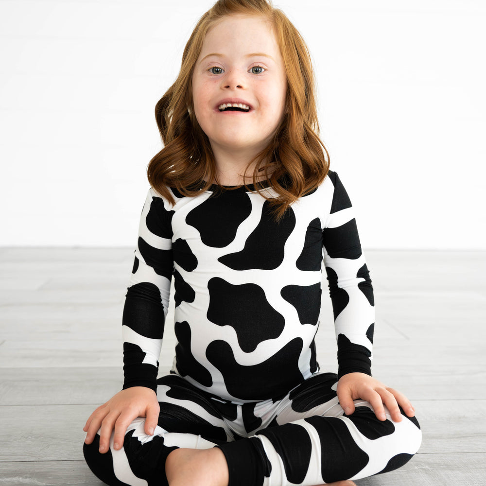 Girl sitting while wearing the Moo Crew Two-Piece Pajama Set