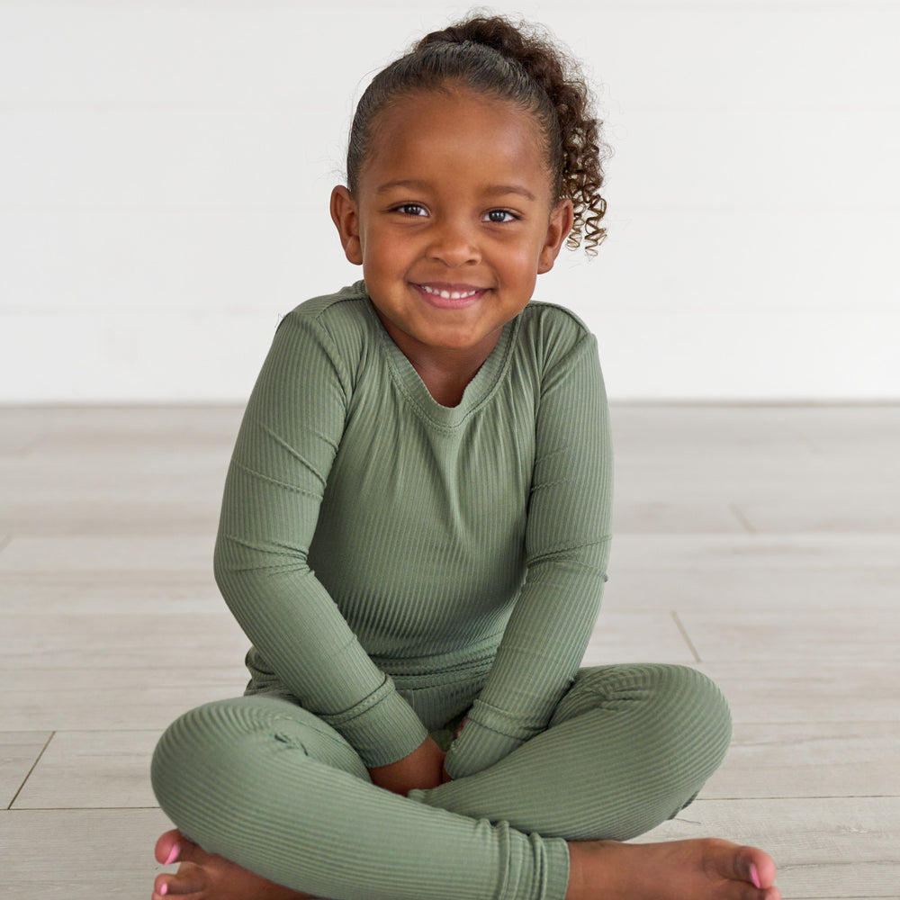 Girl sitting and smiling while wearing the Moss Ribbed Two-Piece Pajama Set