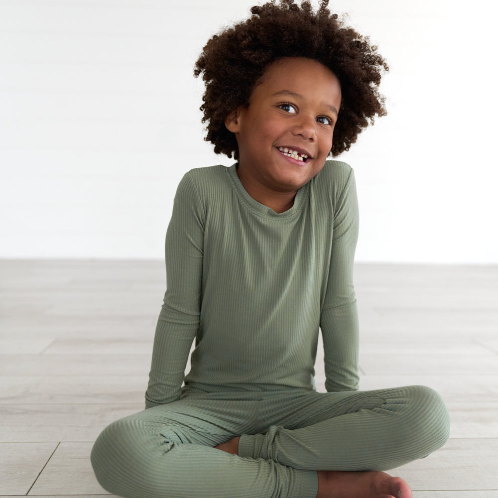 Boy sitting and smiling while in the Moss Ribbed Two-Piece Pajama Set