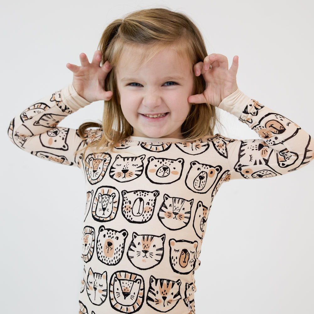 close up image of a child posing wearing a Lions, Tigers, and Bears two piece pj set