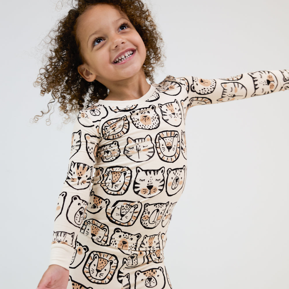 Alternate close up image of a child posing wearing a Lions, Tigers, and Bears two piece pj set