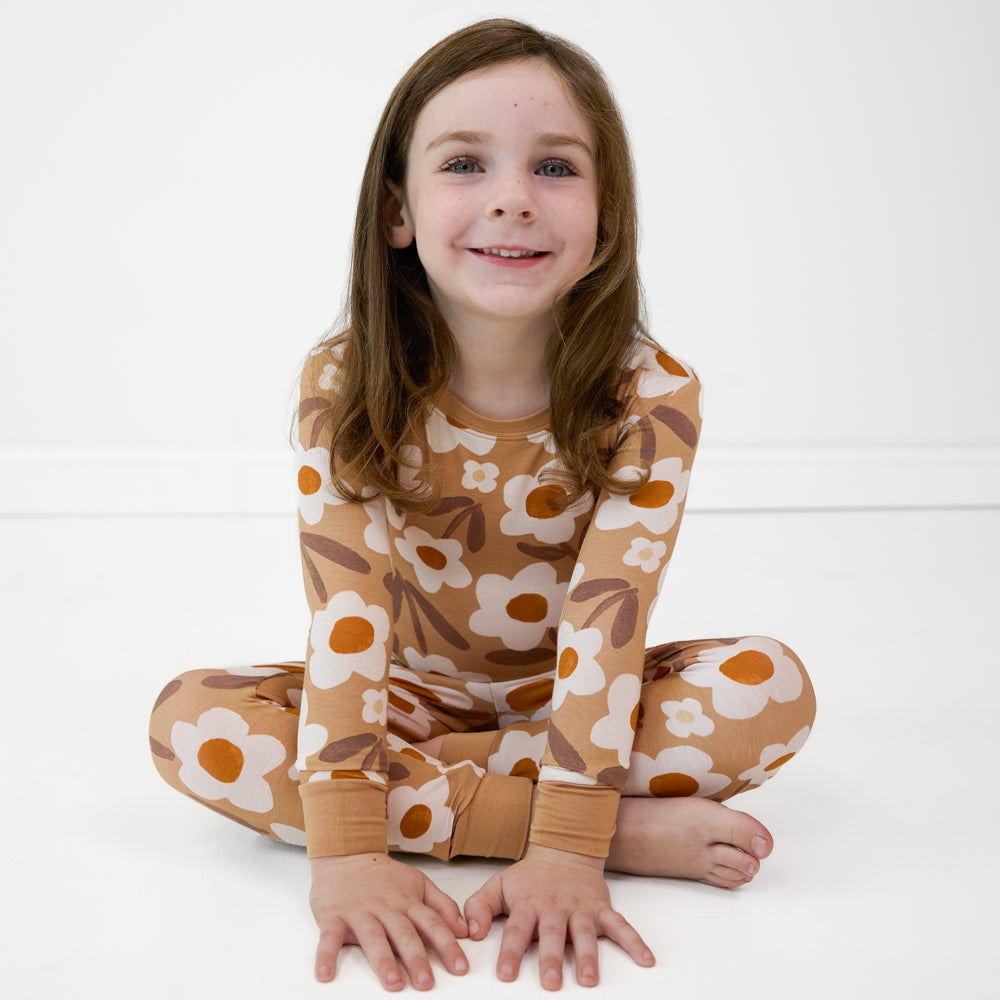 Image of a child sitting wearing a Daisy Daydream two piece pajama set