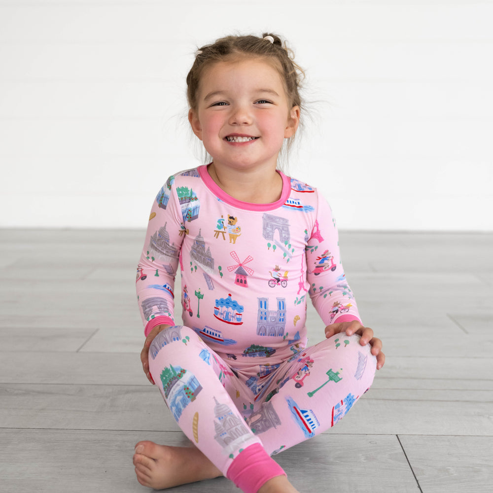 Girl sitting while wearing the Pink Weekend in Paris Two-Piece Pajama Set