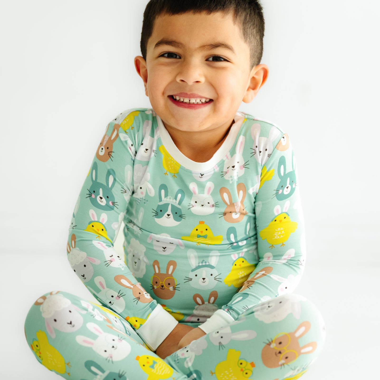 Close up image of a child sitting wearing a Aqua Pastel Parade two piece pajama set