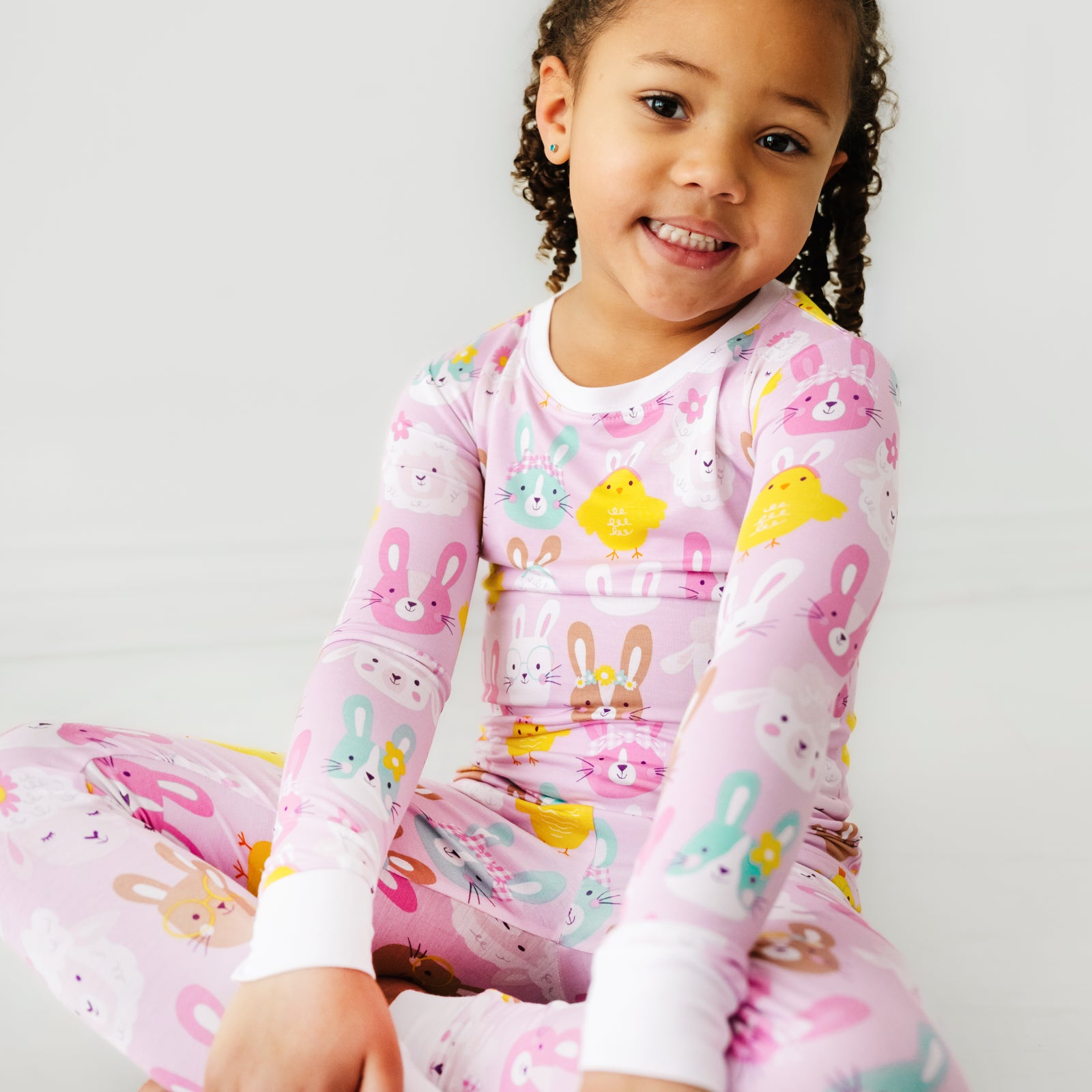 Close up image of a child sitting wearing Pink Pastel Parade two piece pajama set