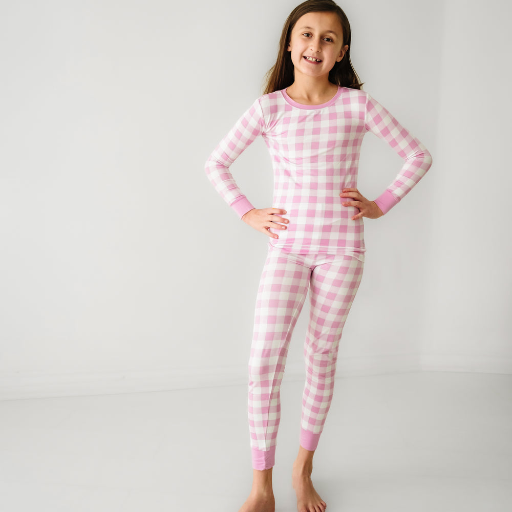 Click to see full screen - Child posing wearing a Pink Gingham two piece pajama set