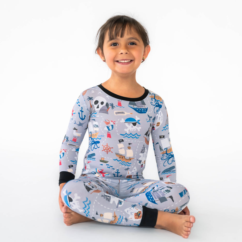 Child sitting while wearing the Pirate's Map Two-Piece Pajama Set