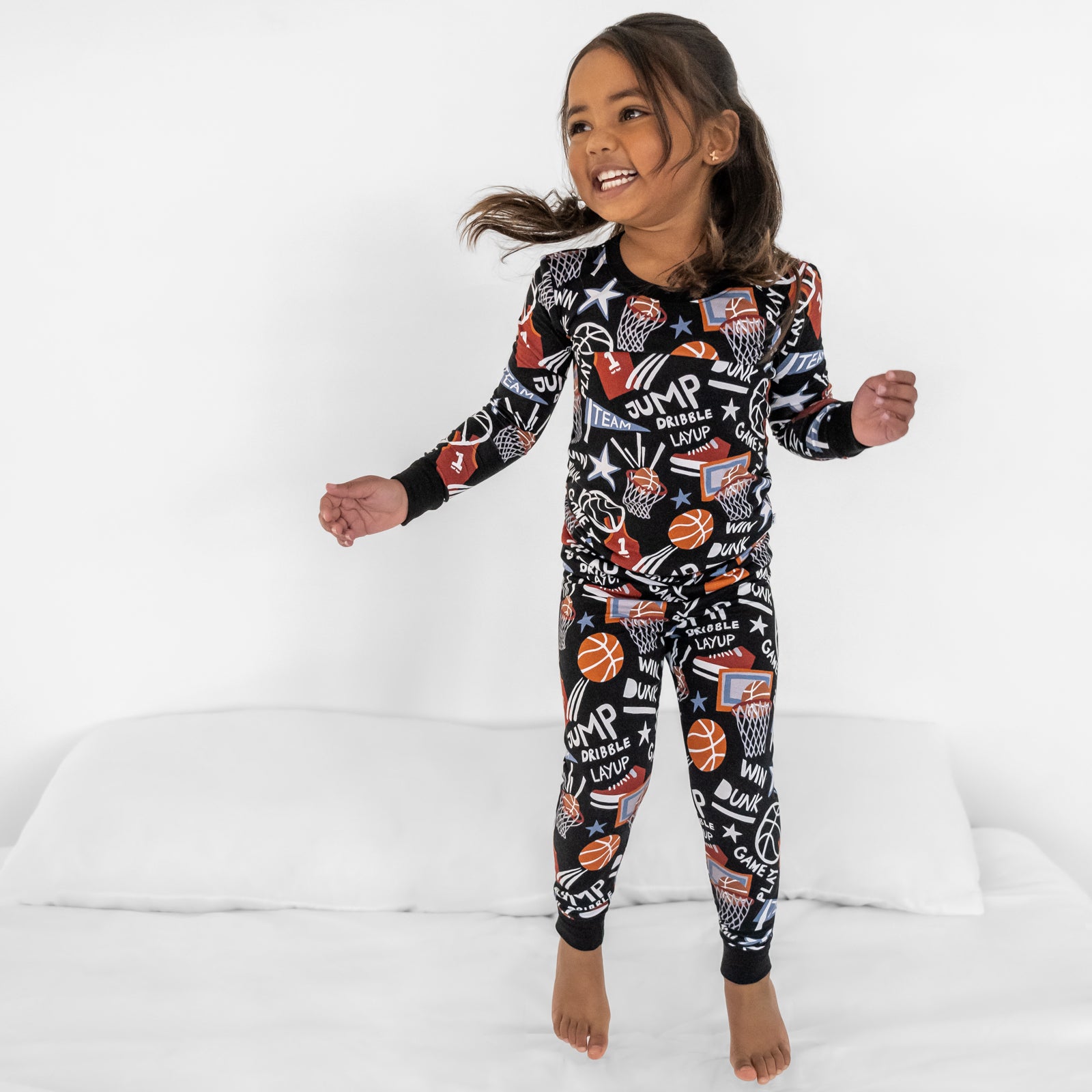 Child jumping on bed wearing the Black Slam Dunk bamboo pajama set