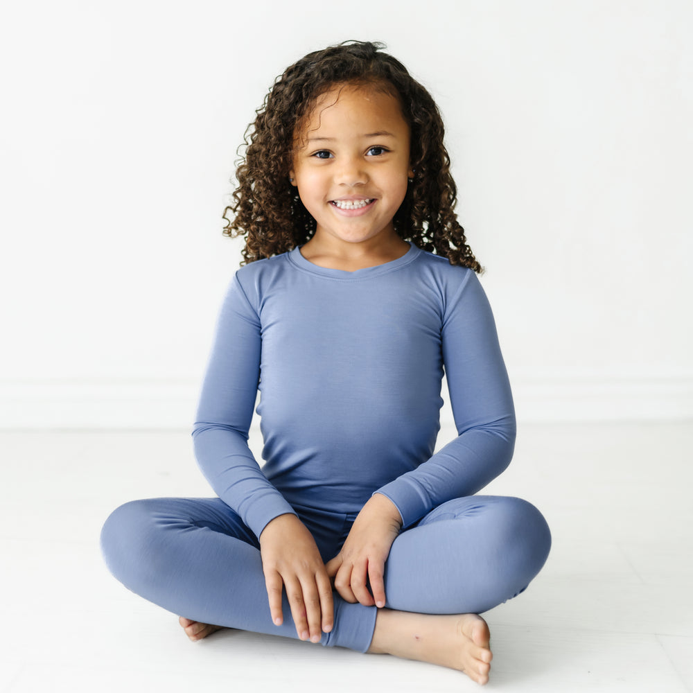 Child sitting wearing a Slate Blue two piece pajama set
