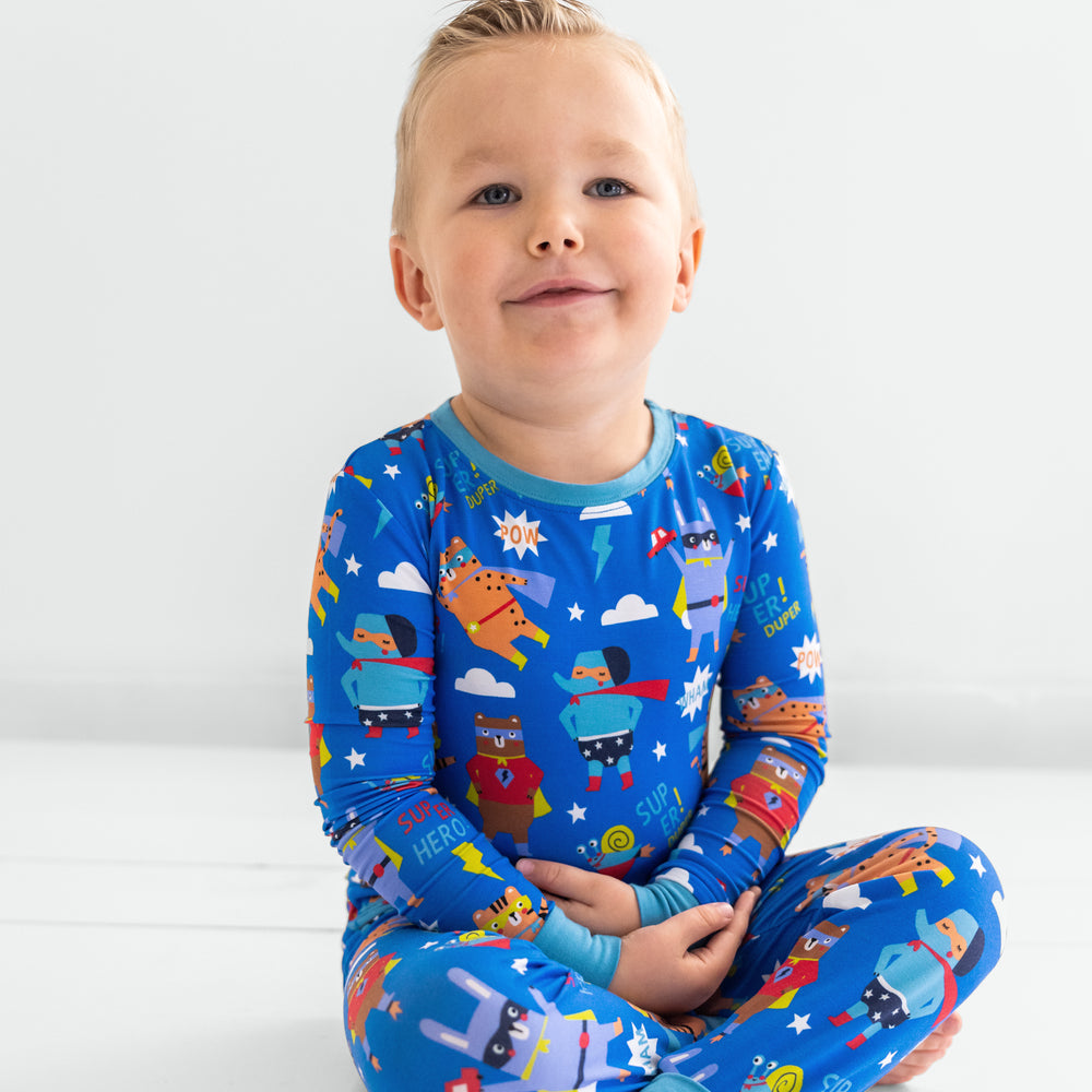 Child sitting wearing the Blue Sleepy Heroes Two-Piece PJ Set