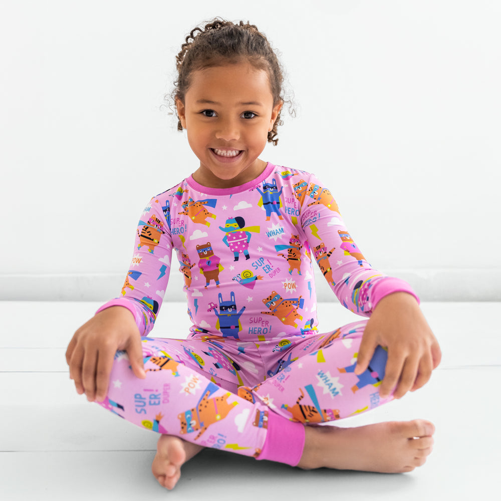 Child sitting in the Pink Sleepy Heroes Two-Piece Long Sleeve & Pants Pajama Set