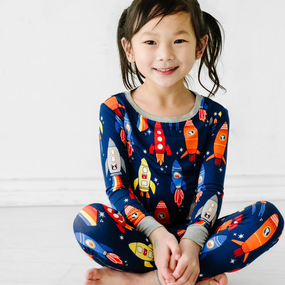 Alternate image of a child sitting wearing a Navy Space Explorer two piece pajama set