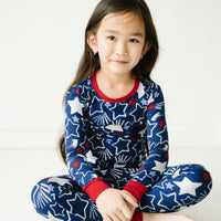 Child sitting wearing a Star Spangled two piece pajama set