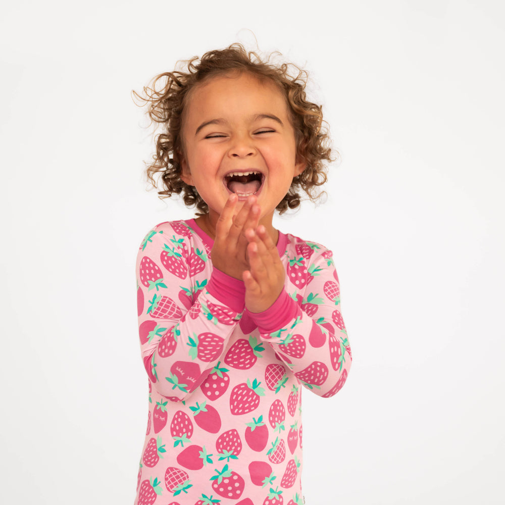 Girl laughing and showing the top of the Sweet Strawberries Two-Piece Pajama Set