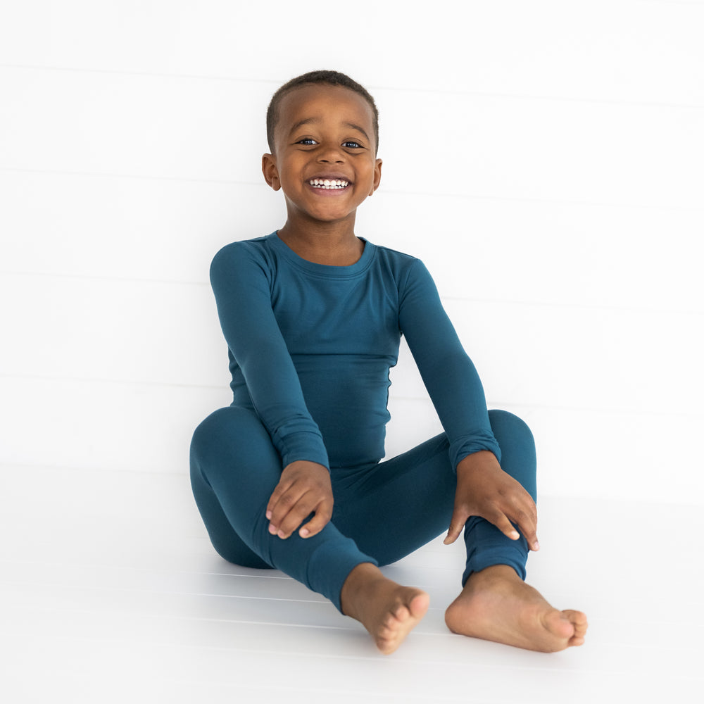 Child sitting wearing a Cozy Twilight Teal two piece pj set