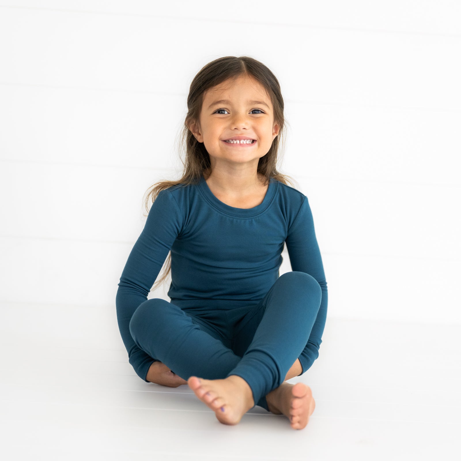 Alternate image of a child sitting wearing a Cozy Twilight Teal two piece pj set