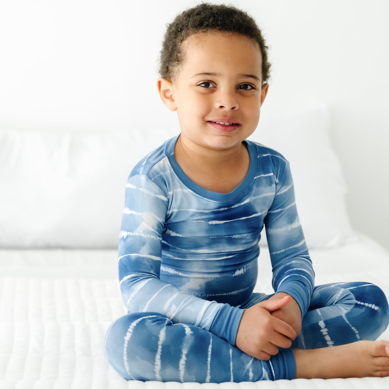 Child sitting on the ground wearing a Blue Tie Dye Dreams two-piece pajama set