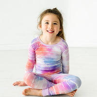 Child sitting on the ground wearing a Pastel Tie Dye Dreams two-piece pajama set