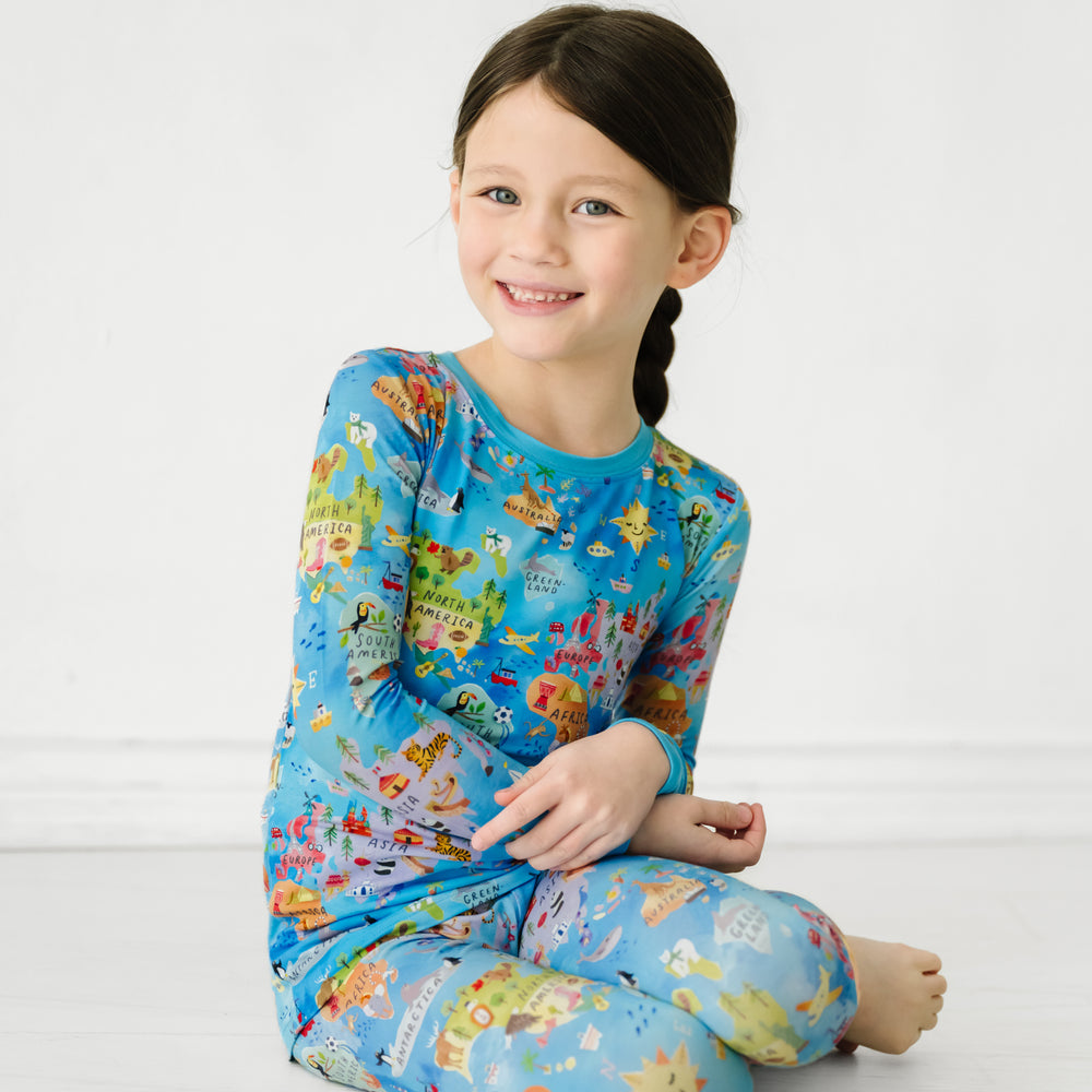 Child sitting wearing an Around the World two piece pajama set