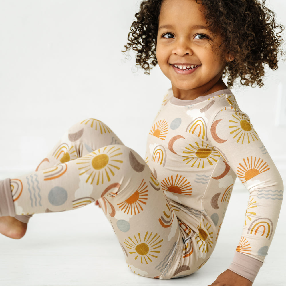 Child sitting and posing wearing a Desert Sunrise two piece pajama set