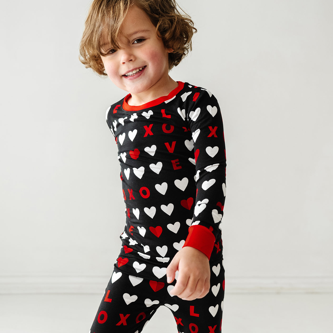Close up image of a child walking wearing Black XOXO two piece pajama set