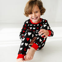 Child sitting wearing a Black XOXO two piece pajama set