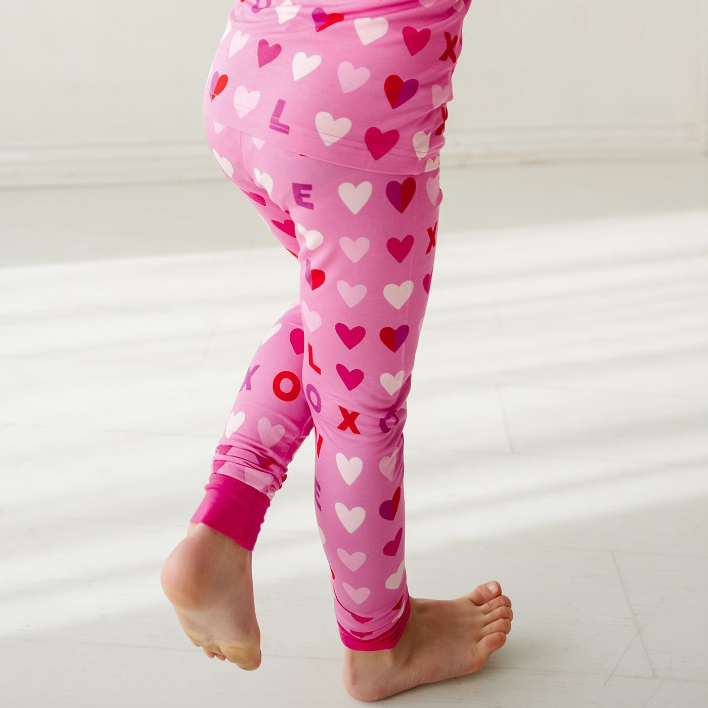 Child wearing a Pink XOXO two piece pajama set showing off the pajama pants