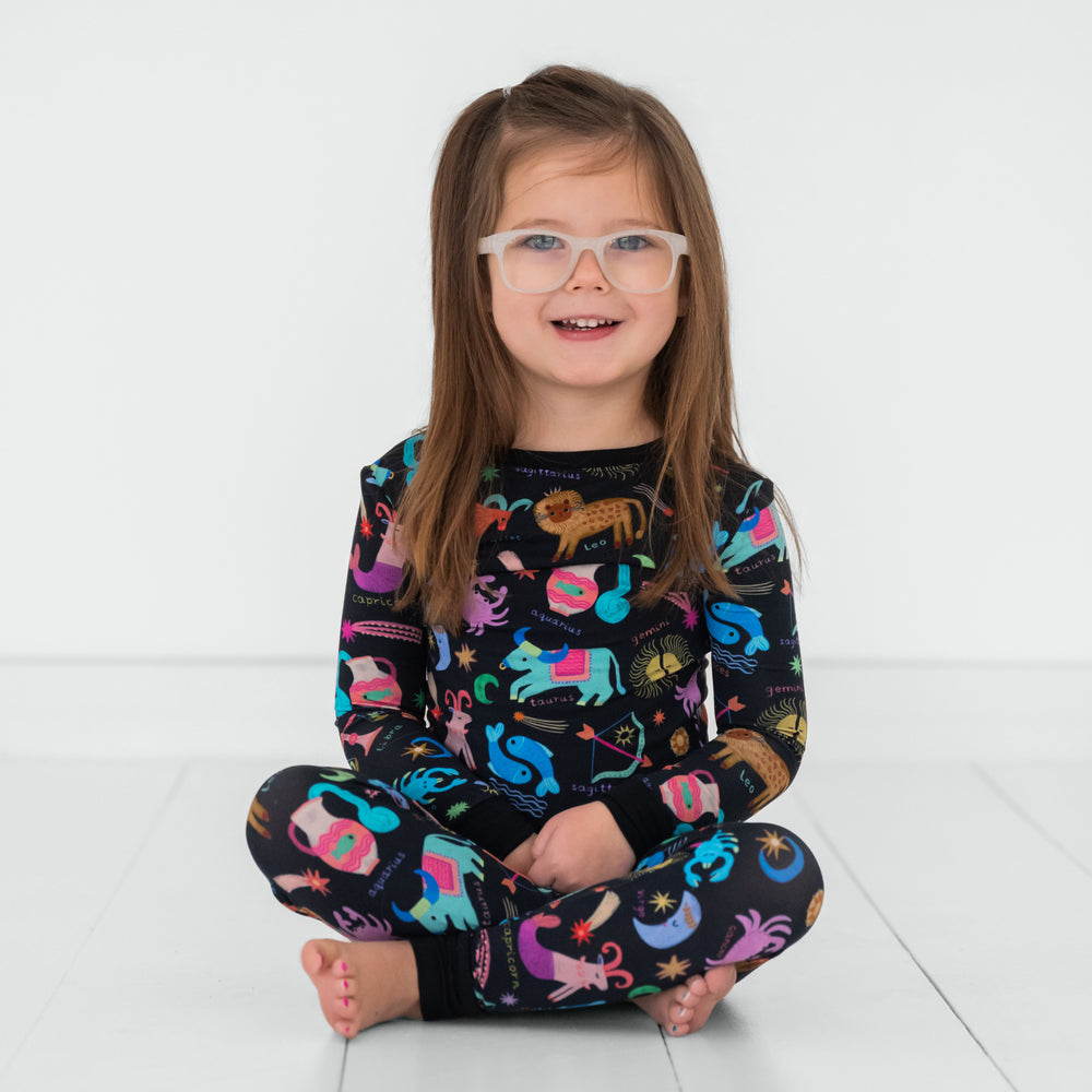 Child sitting wearing a Star Signs two piece pajama set