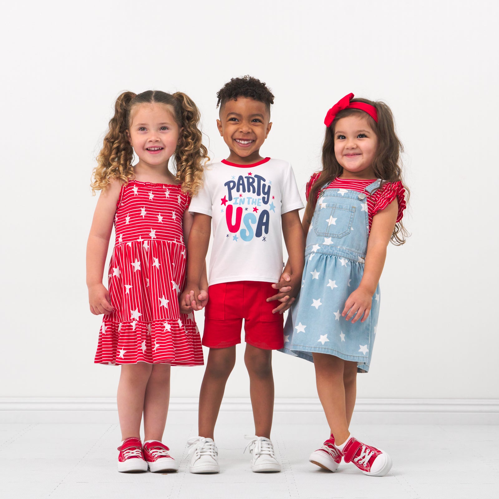 Three children holding hands wearing coordinating 4th of July Play outfits