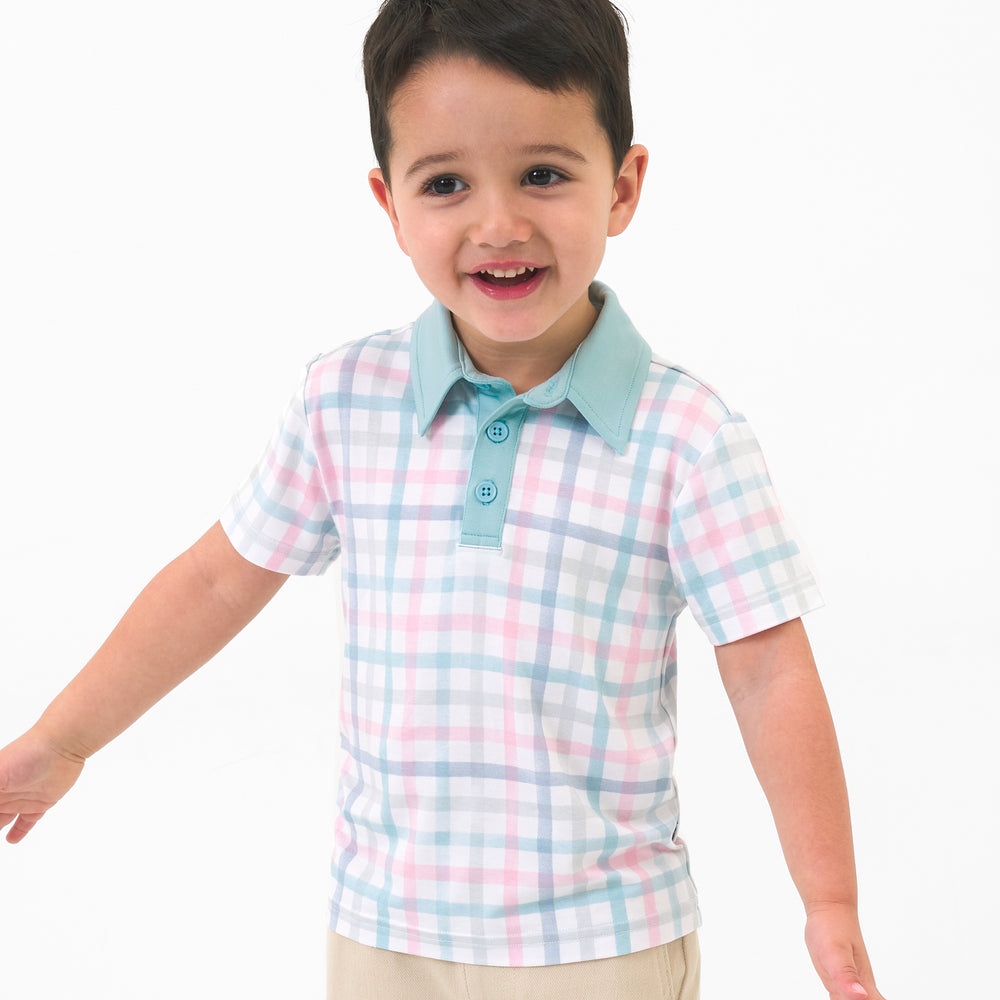 Close up image of a child wearing a Playful Plaid polo shirt and coordinating shorts